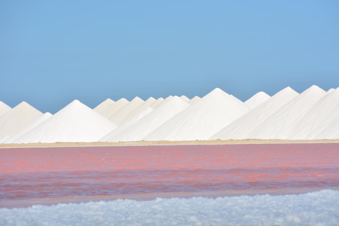 The salt pans in the island's south — the pink water coloured by halophilic algae, white pyramids of harvested salt behind