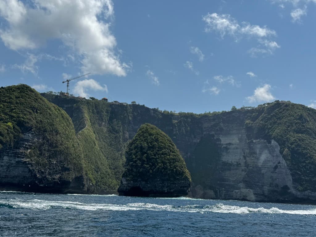 The limestone cliffs of Nusa Penida seen from the water — sheer walls dropping straight to the sea